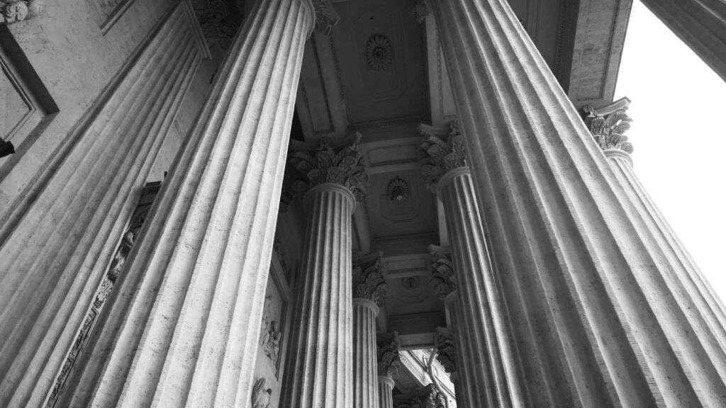 Colonnes classiques en pierre dans un bâtiment historique en noir et blanc.